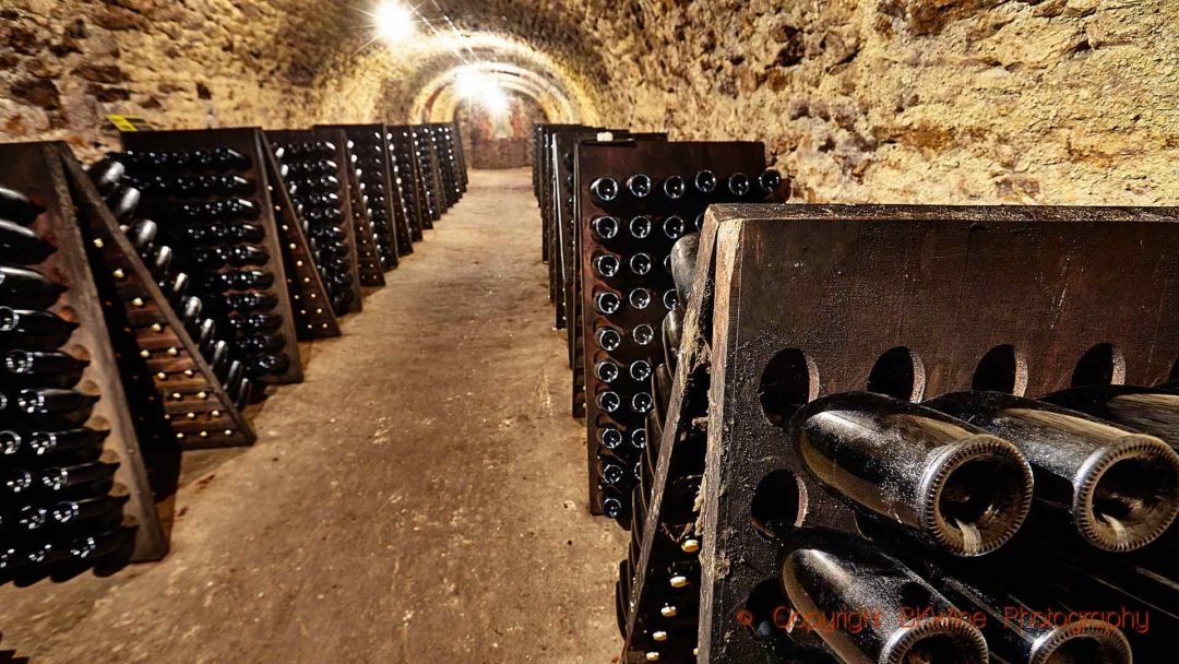 Bottles in pupitres in a carved-out cellar in Champagne
