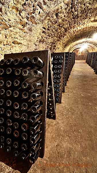 Bottles in pupitres in a carved-out cellar in Champagne