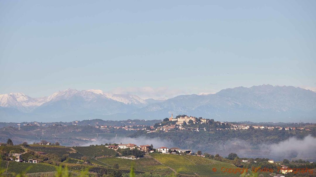 Vineyards, a castle on a hilltop and snowy mountains in Piedmont