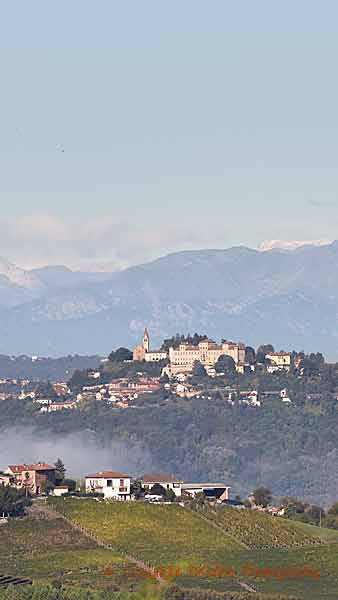 Vineyards, a castle on a hilltop and snowy mountains in Piedmont