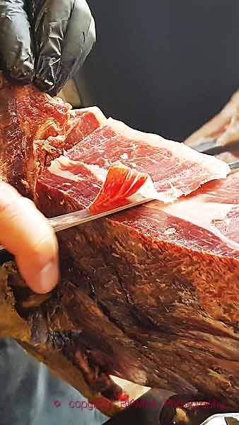 Cutting a slice of the delicious Spanish dry-cured ham, jamon iberico